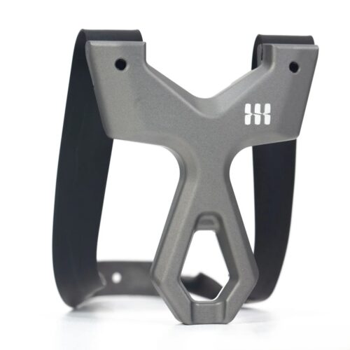 Grey bicycle water bottle cage with a wide, angular silhouette and a hexagonal bottle opening at the bottom, mounted between two black straps/arms.